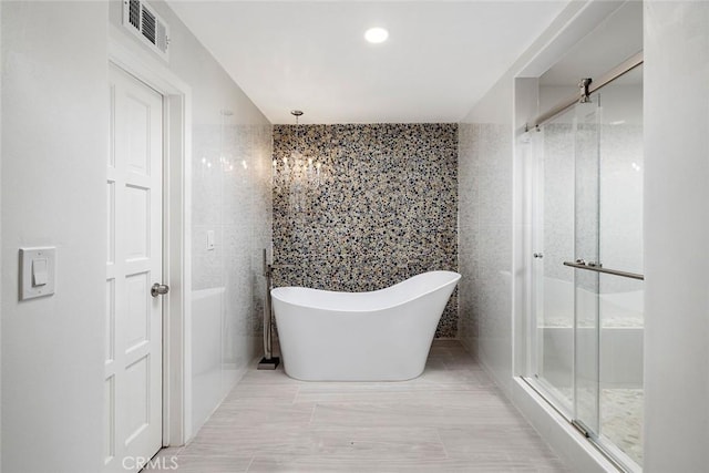 bathroom featuring independent shower and bath and tile walls