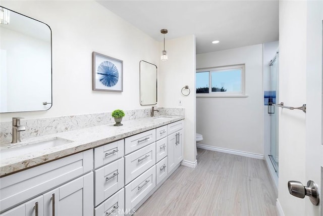 bathroom featuring a shower with door, vanity, wood-type flooring, and toilet