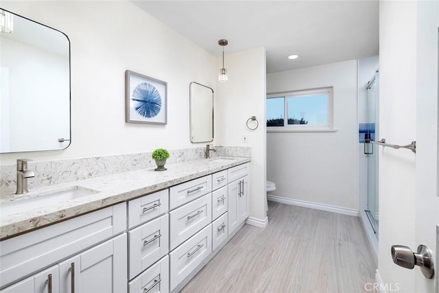 16592 Grimaud Ln, Huntington Beach, CA 92649 - bathroom featuring toilet, double vanity, a shower with shower door, baseboards, and wood finished floors