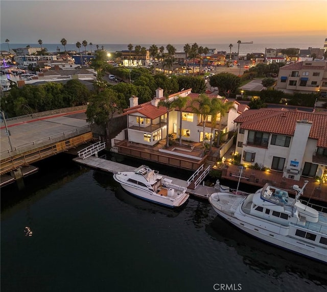 aerial view at dusk featuring a water view