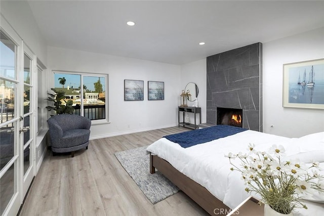 bedroom with a large fireplace and light hardwood / wood-style flooring