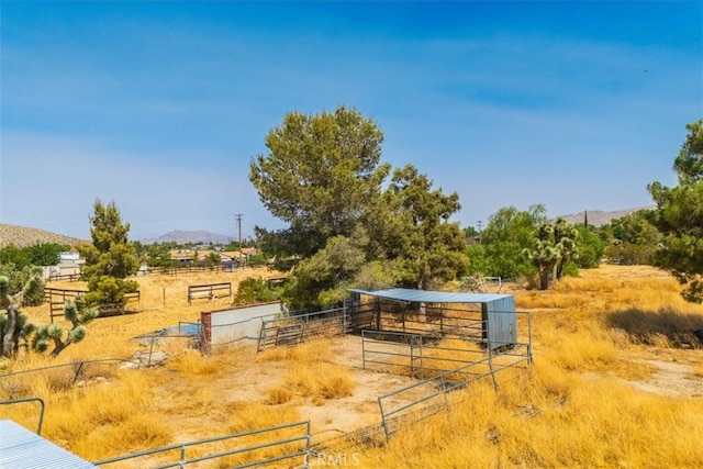 view of yard featuring a mountain view, an outdoor structure, and a rural view