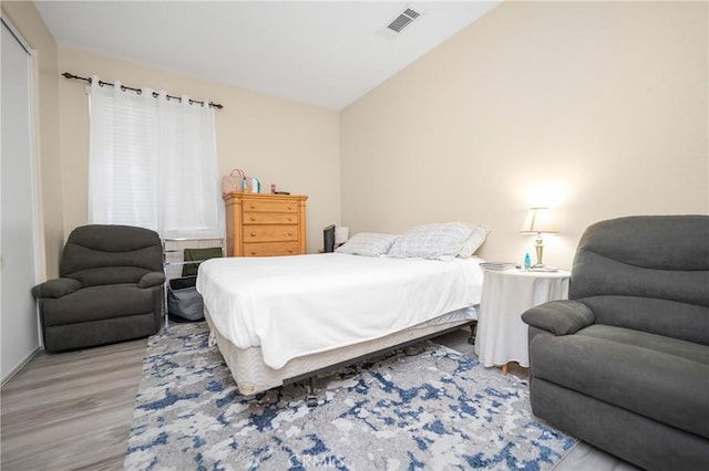 bedroom with vaulted ceiling, wood finished floors, and visible vents