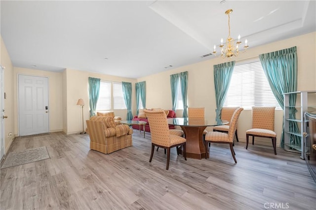 dining area featuring light wood-style floors, baseboards, and an inviting chandelier