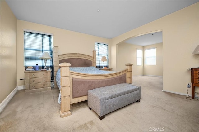 bedroom featuring arched walkways, carpet floors, and baseboards