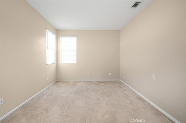 unfurnished room with light colored carpet, visible vents, and baseboards