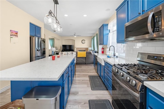 kitchen with open floor plan, stainless steel appliances, and blue cabinetry