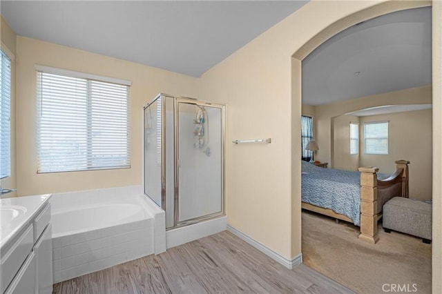 ensuite bathroom with wood finished floors, a shower stall, a bath, and ensuite bathroom