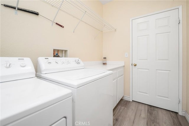 laundry room featuring light wood-style floors, washer and dryer, and cabinet space