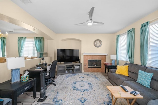 living room with a healthy amount of sunlight, a ceiling fan, and a tile fireplace