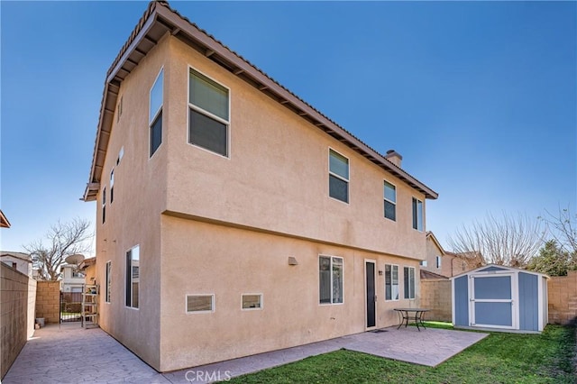 rear view of house featuring a storage unit, a patio area, an outdoor structure, and stucco siding