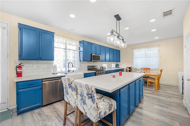 kitchen with blue cabinets, stainless steel appliances, and a sink