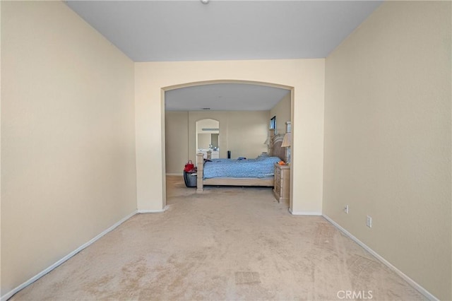 carpeted bedroom with arched walkways and baseboards