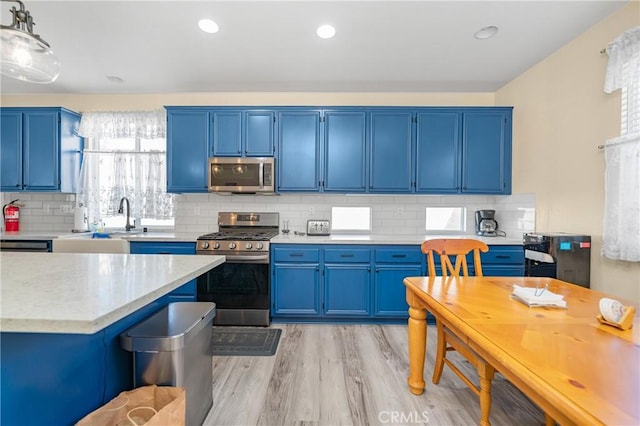 kitchen with blue cabinets, light wood-style floors, stainless steel appliances, and light countertops