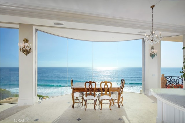 dining room featuring a water view, a view of the beach, a notable chandelier, and ornamental molding