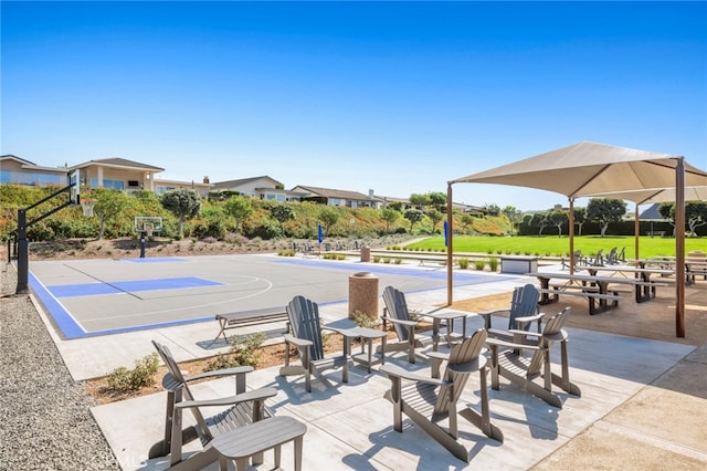 view of community featuring a patio and basketball hoop