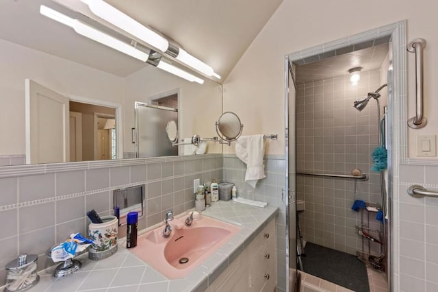 bathroom featuring lofted ceiling, decorative backsplash, a shower with door, vanity, and tile walls