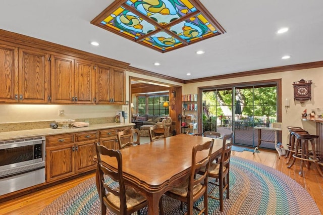 dining room with light wood-type flooring and crown molding