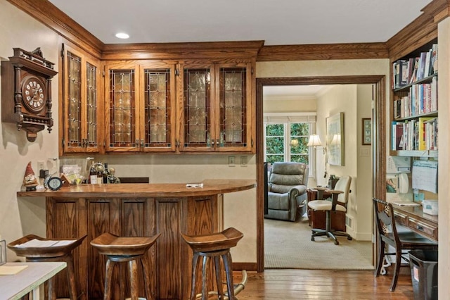 bar featuring ornamental molding and dark wood-type flooring