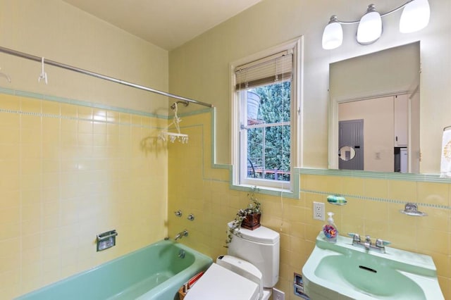 full bathroom with sink, tiled shower / bath, tile walls, and toilet