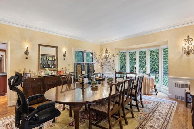 dining space with radiator, light hardwood / wood-style floors, plenty of natural light, and crown molding