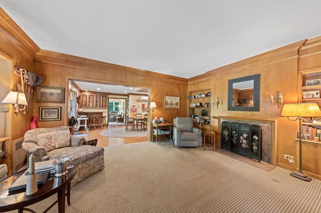 living room featuring built in features, ornamental molding, and wood walls