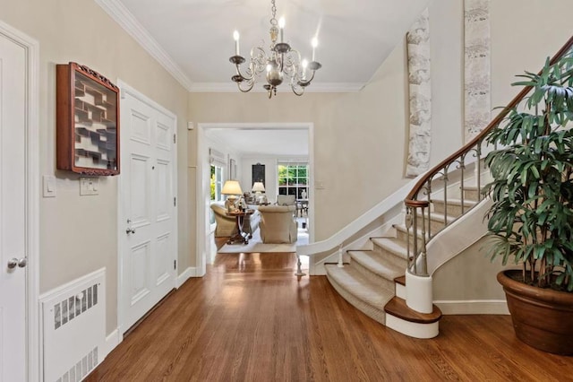 entryway featuring radiator, crown molding, hardwood / wood-style floors, and an inviting chandelier