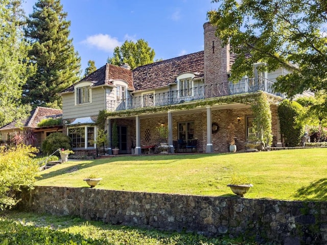 back of house featuring a lawn and a balcony