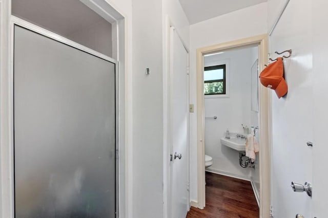 bathroom featuring wood-type flooring, toilet, an enclosed shower, and sink