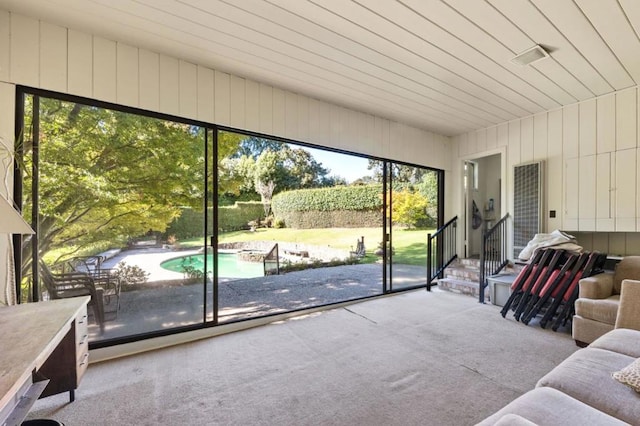 interior space with carpet flooring, a healthy amount of sunlight, and wood walls