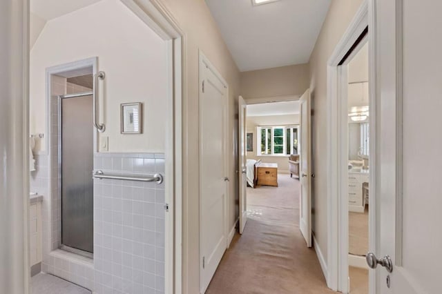 hall with vaulted ceiling, light carpet, and tile walls