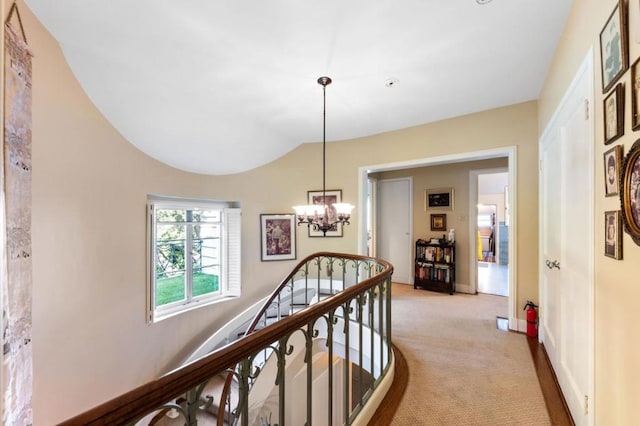 hall featuring light colored carpet and a notable chandelier