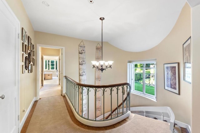 corridor with a notable chandelier and light colored carpet