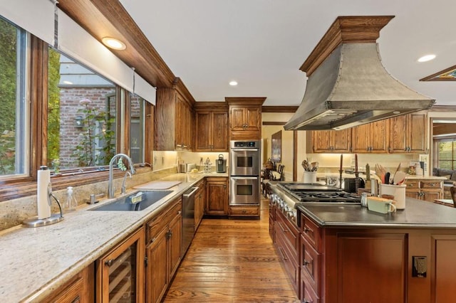 kitchen featuring ornamental molding, custom range hood, stainless steel appliances, sink, and light hardwood / wood-style flooring