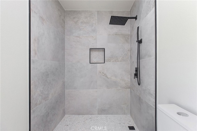 bathroom featuring a tile shower and toilet