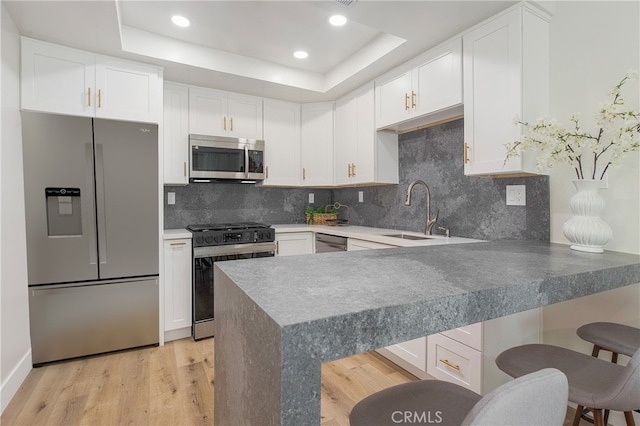 kitchen with appliances with stainless steel finishes, kitchen peninsula, white cabinetry, and a kitchen breakfast bar