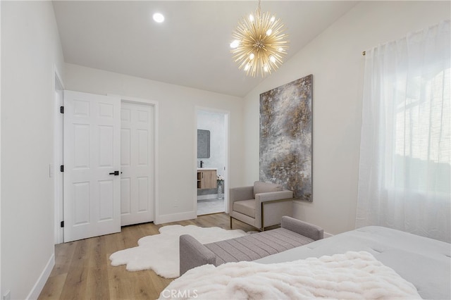 bedroom featuring a closet, hardwood / wood-style flooring, lofted ceiling, an inviting chandelier, and ensuite bath