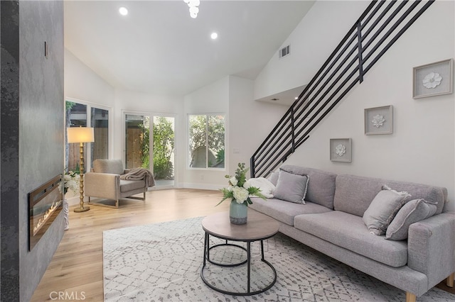 living room featuring light hardwood / wood-style flooring and high vaulted ceiling