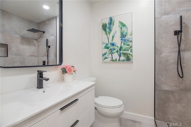 bathroom featuring a tile shower, tile patterned flooring, vanity, and toilet