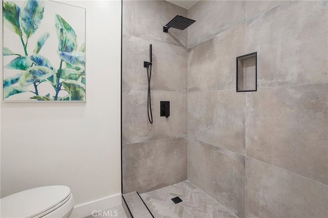 bathroom with a tile shower and toilet