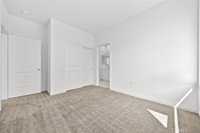 unfurnished bedroom with light colored carpet, ensuite bath, and a closet