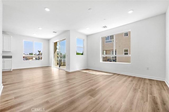 unfurnished living room featuring light wood-type flooring and a healthy amount of sunlight