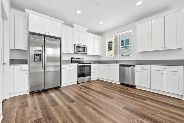 kitchen featuring dark hardwood / wood-style floors, white cabinetry, sink, and appliances with stainless steel finishes