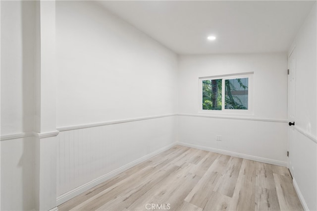 spare room with lofted ceiling and light hardwood / wood-style floors