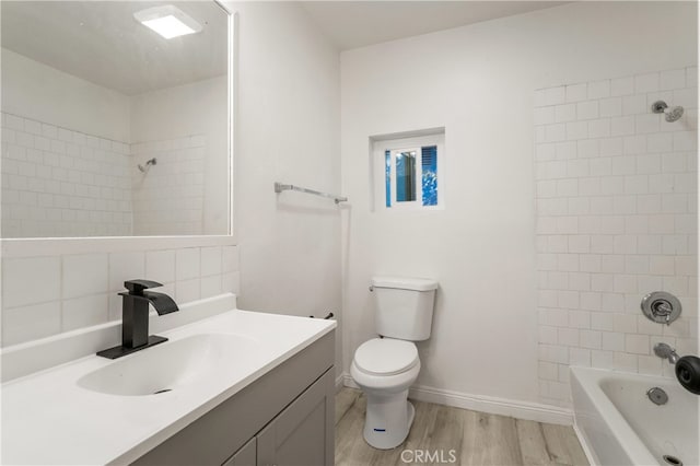 full bathroom with hardwood / wood-style floors, tiled shower / bath, vanity, and toilet