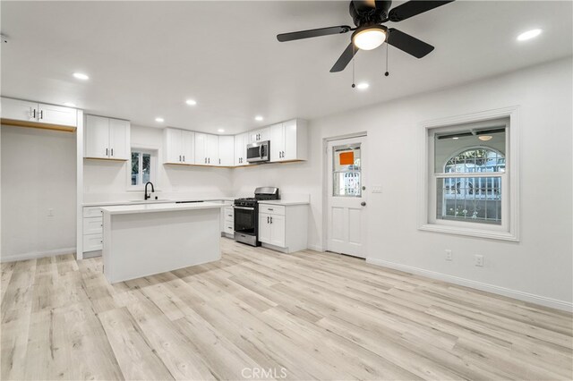 kitchen with appliances with stainless steel finishes, light wood-type flooring, and white cabinetry