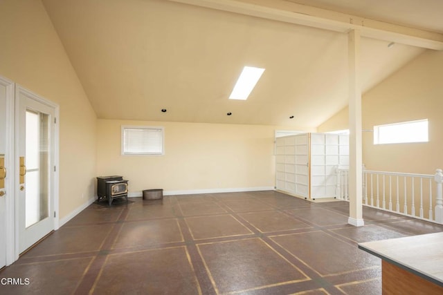 empty room featuring beamed ceiling, a wood stove, and high vaulted ceiling