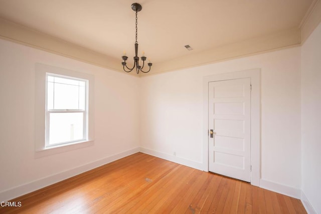 unfurnished room with a chandelier and hardwood / wood-style flooring