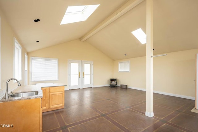 interior space featuring beam ceiling, a skylight, sink, high vaulted ceiling, and light brown cabinetry