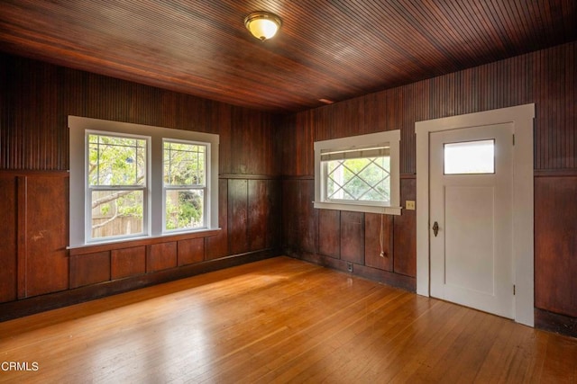 entryway with light wood-type flooring, wooden ceiling, and wooden walls